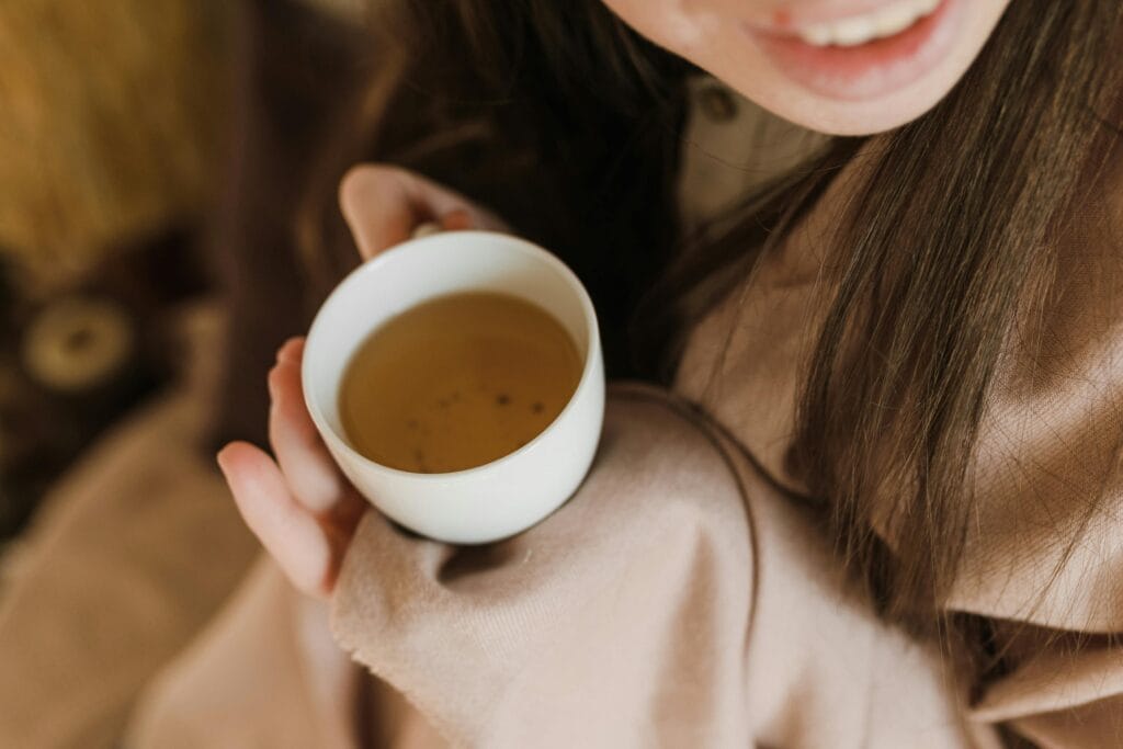 woman drinking herbal tea morning sunlight kitchen